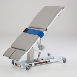 White medical examination table with wheels.