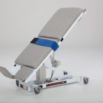 White medical examination table on wheels.