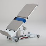 White medical examination table on wheels.